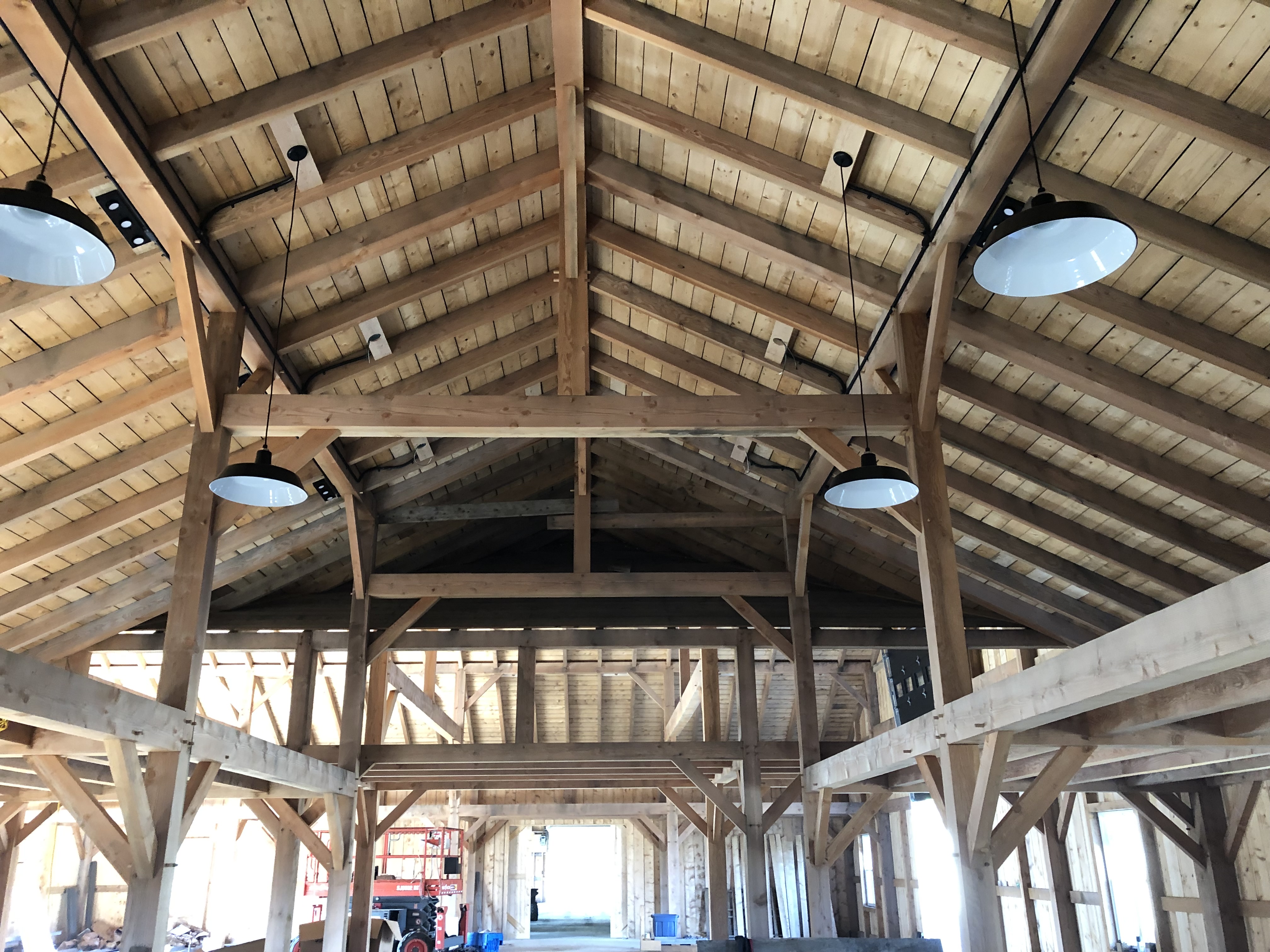 Interior of a timber-frame barn showing lighting installation and structure during construction
